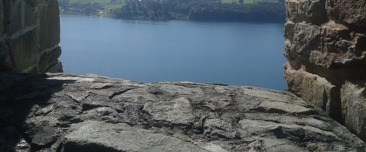 A stone structure overlooking a lake with mountains in the background.