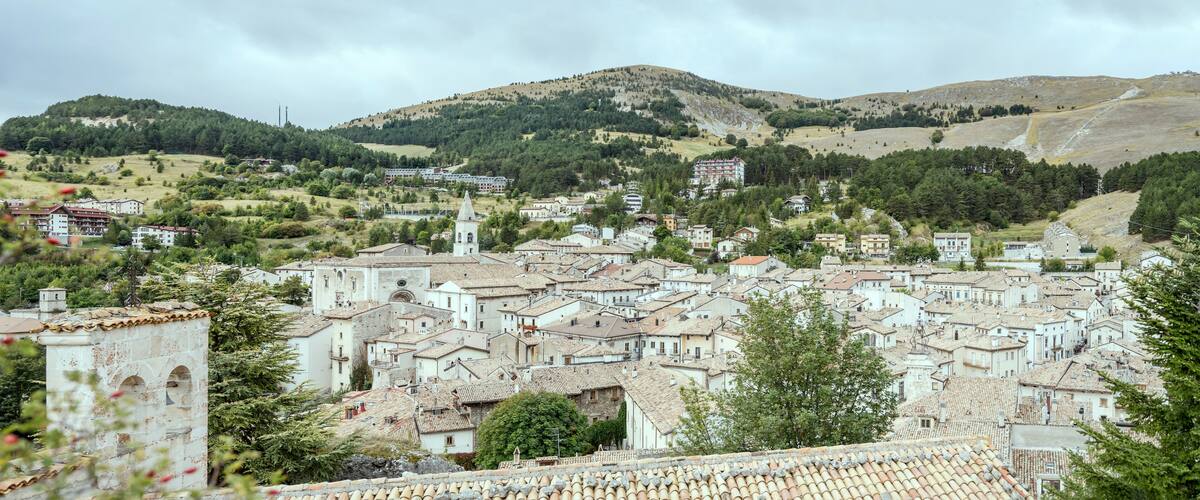 A town with historic buildings, a prominent church, and rolling hills in the background.
