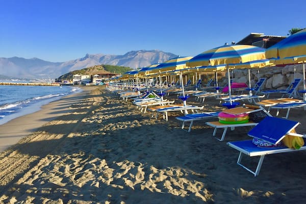 Une plage bordée de rangées de parasols et de chaises longues.