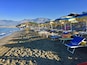 A beach with rows of sun umbrellas and lounge chairs.