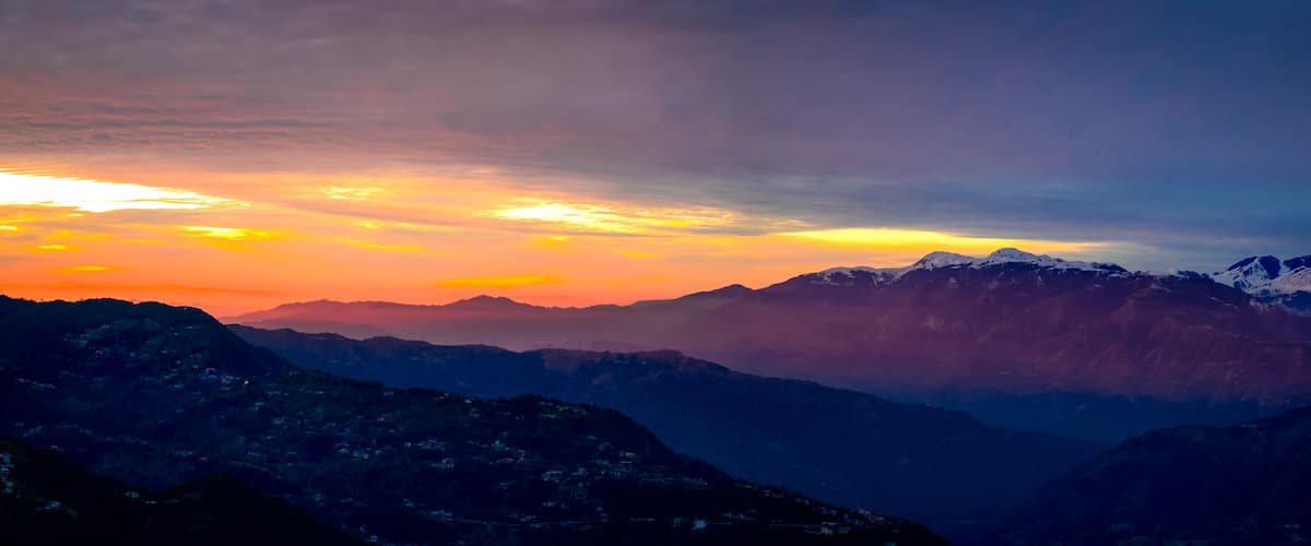 Panoramic view of sunrise over the mountains. Colourful, vibrant, burning sunset, skies, dramatic clouds over the Himalayan mountains. On Trek to Dalhousie, Himachal Pradesh, India.