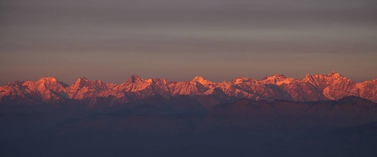 A mountain range with snow-capped peaks during sunset.