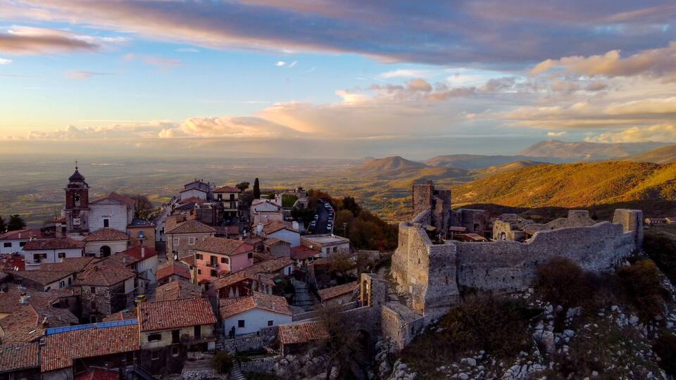 A historic town with a prominent church tower, cobblestone streets, and a castle ruin.