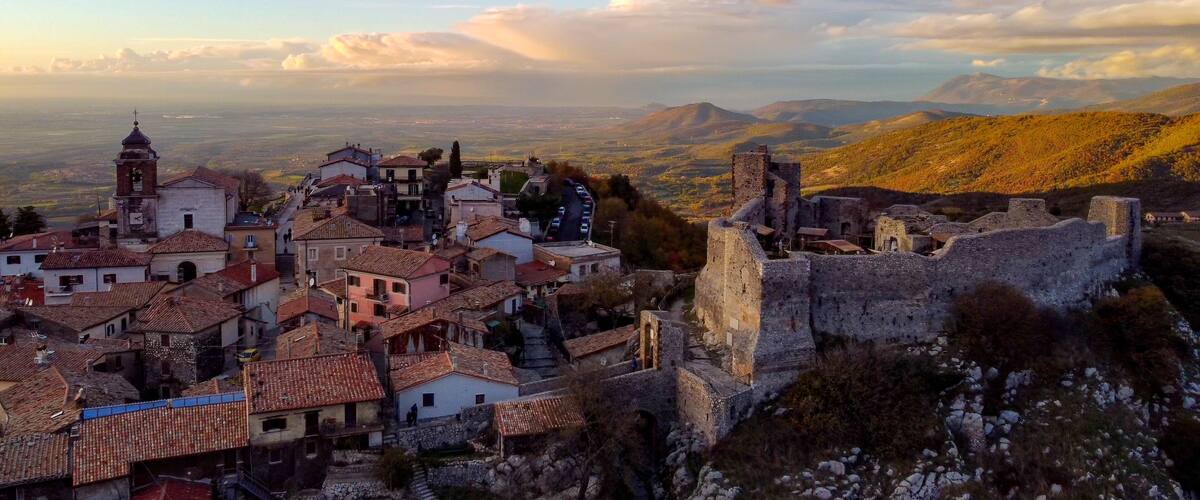 A historic town with a prominent church tower, cobblestone streets, and a castle ruin.
