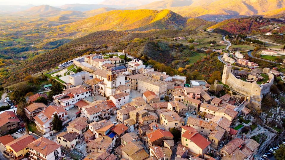 A historic town with medieval architecture, surrounded by rolling hills and a fortified wall.