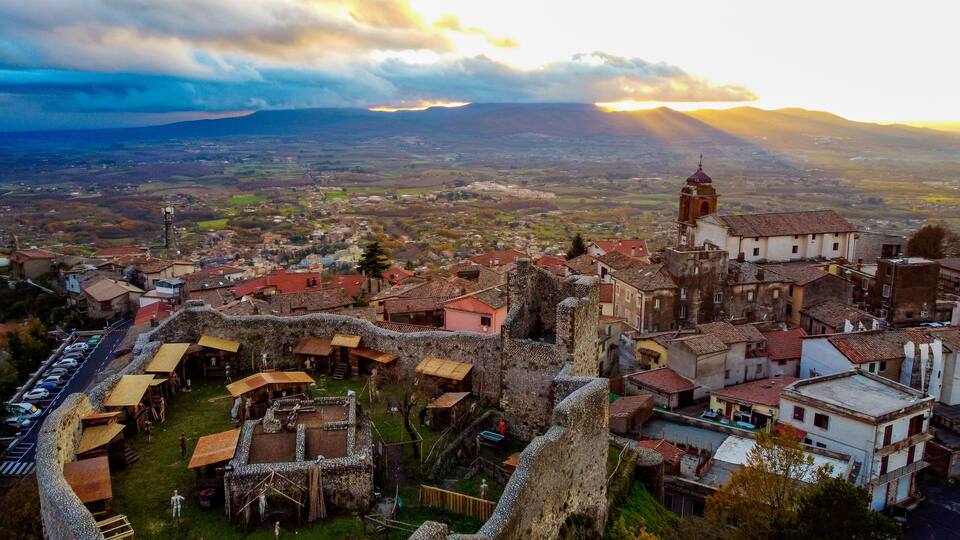 A historic town with a prominent church tower, surrounded by traditional buildings and a stone wall.