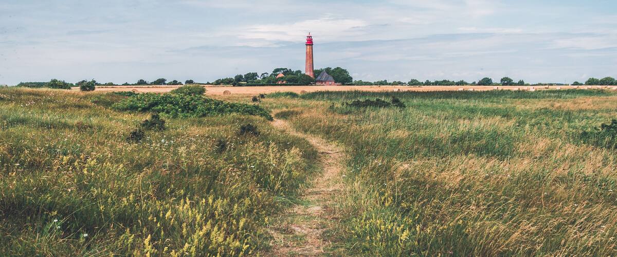A lighthouse on a grassy hill with a clear sky.
