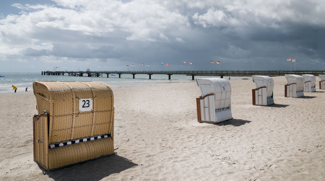 Empty beach chairs on the Baltic Sea beach and pier with the flags of German constituent states and cities. Grossenbrode, Schleswig- Holstein, Germany