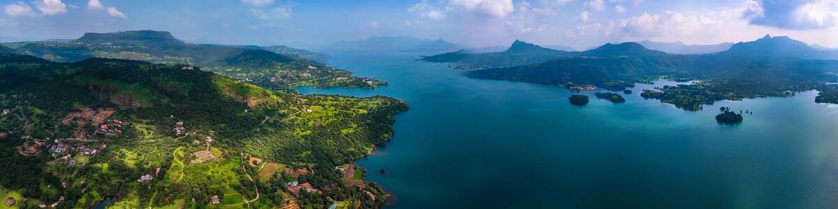 Aerial view of deep blue waters reflecting the sky, embraced by verdant hills and scattered islands, Lonavala, Maharashtra, India.