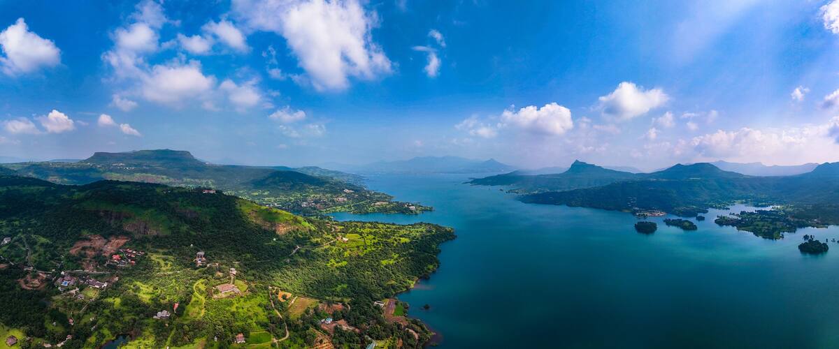 Aerial view of deep blue waters reflecting the sky, embraced by verdant hills and scattered islands, Lonavala, Maharashtra, India.