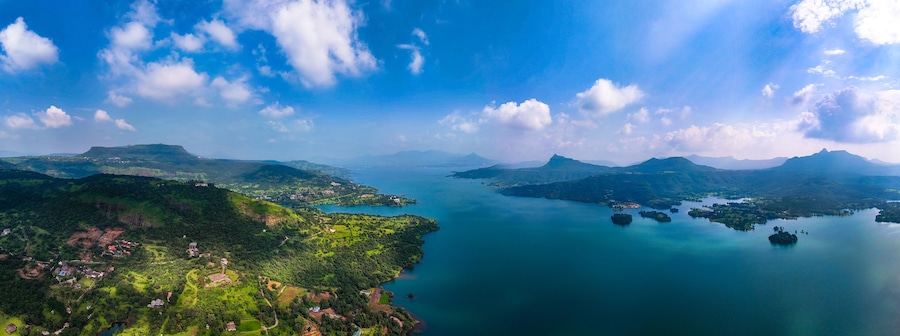 Aerial view of deep blue waters reflecting the sky, embraced by verdant hills and scattered islands, Lonavala, Maharashtra, India.