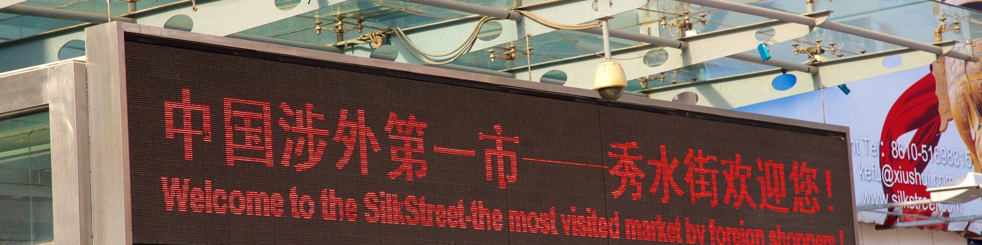Placa digital com caracteres chineses e texto em inglês dando as boas-vindas aos visitantes ao mercado Silk Street.