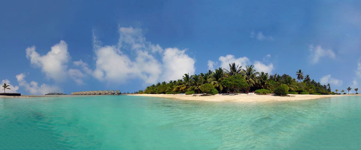 A tropical island with clear turquoise waters, a sandy beach, and lush greenery.