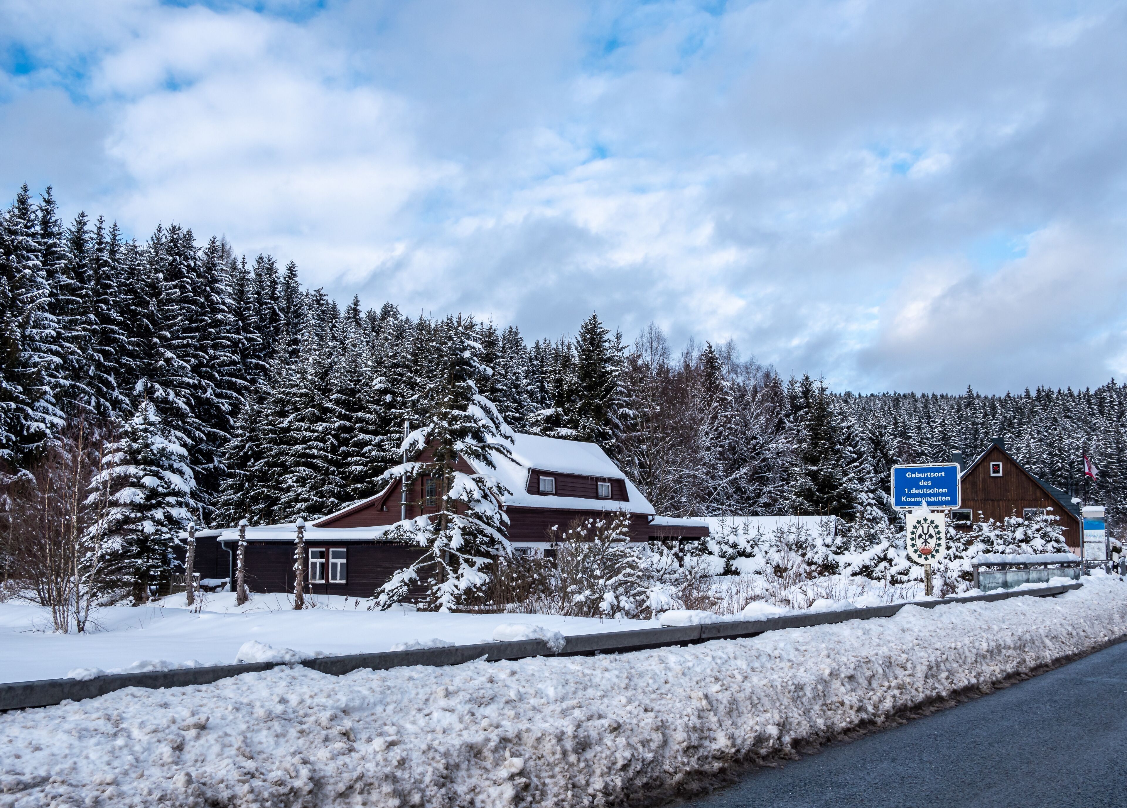 A snow-covered cabin with a sign indicating it's a German birth tourism location.