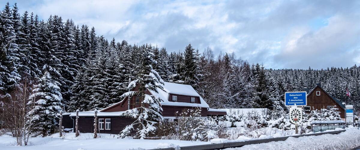A snow-covered cabin with a sign indicating it's a German birth tourism location.