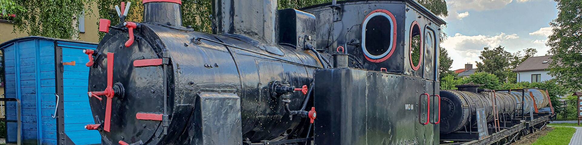 A black steam locomotive with red wheels and a blue caboose on a track.