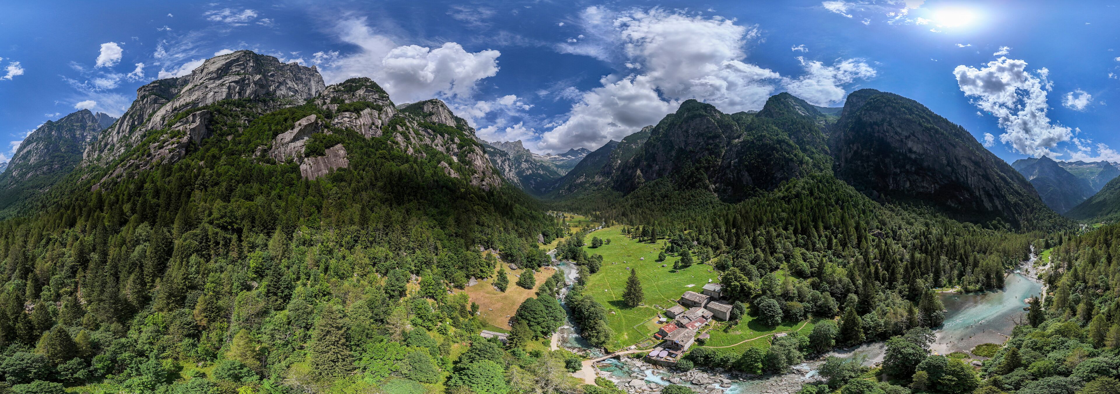 A mountainous landscape with a river, a small settlement, and dense forests.