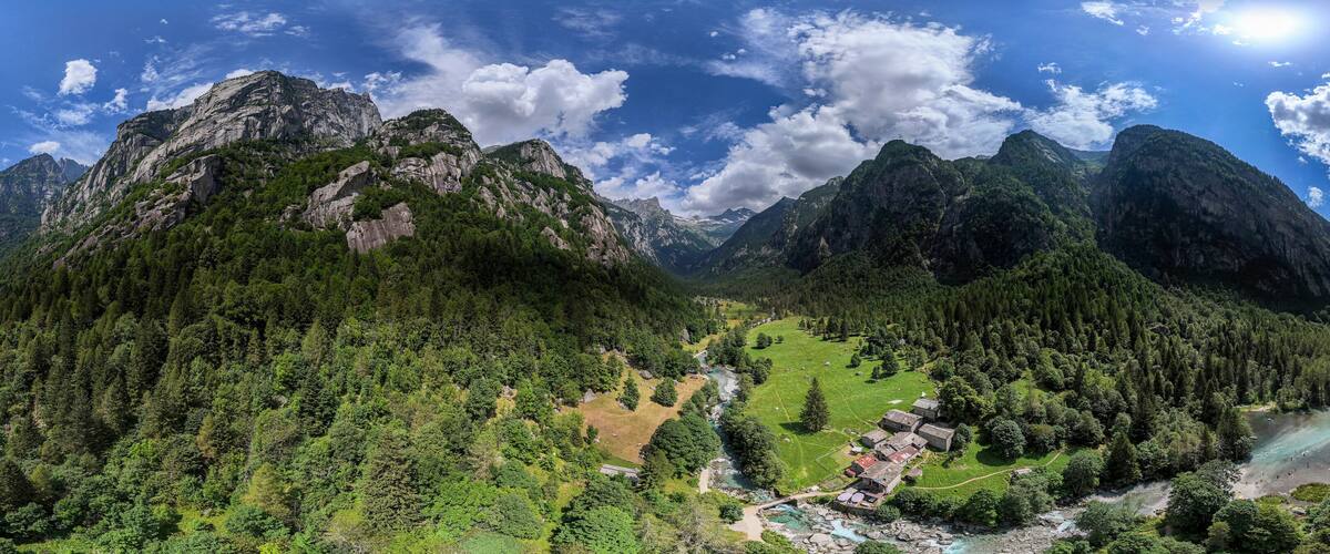 A mountainous landscape with a river, a small settlement, and dense forests.