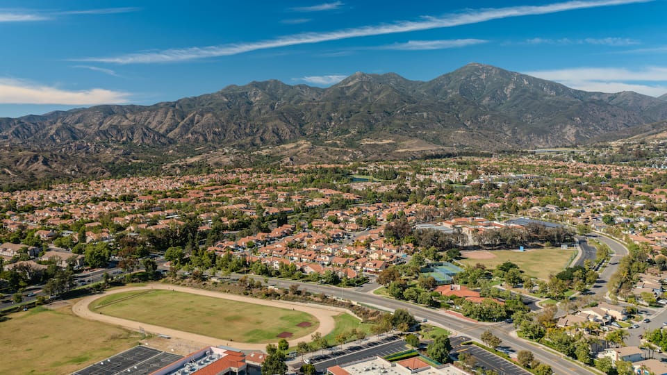A residential area with houses, roads, and mountains in the background.