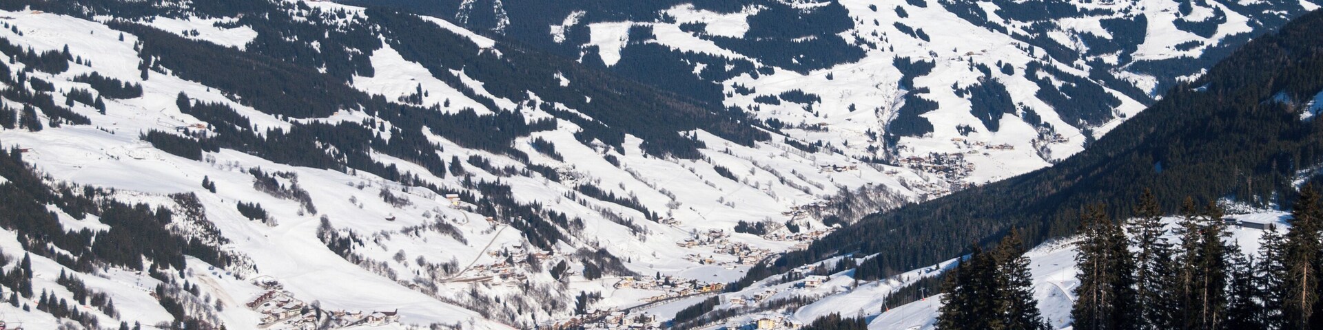 Downhill slope and apres ski mountain hut with restaurant terrace in Saalbach Hinterglemm Leogang winter resort, Tirol, Austria, Europe. Sunny day shot