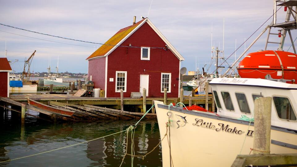 A red building with a white door and windows, a dock with boats, and a clear sky.
