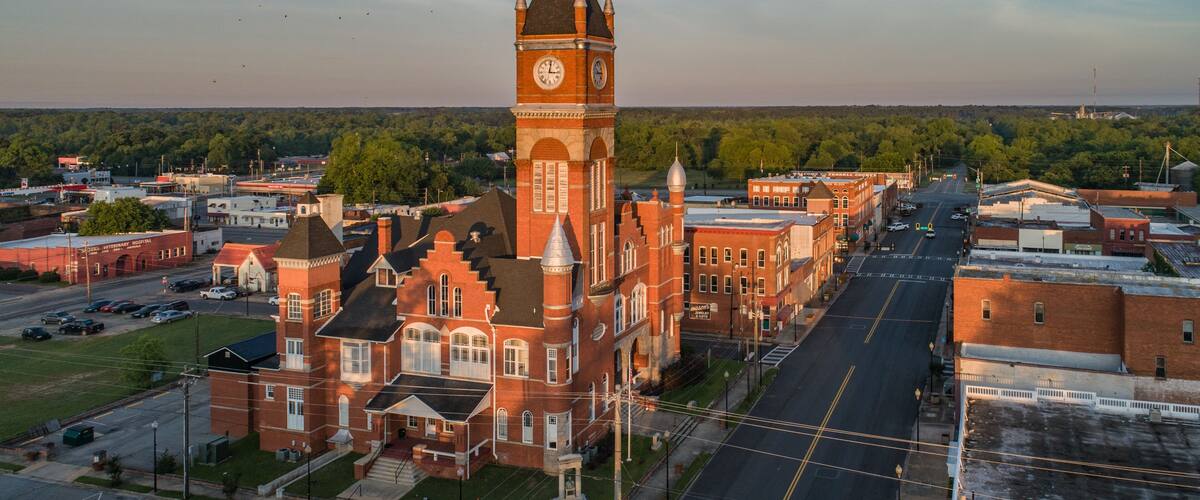 A historic building with a clock tower, surrounded by a town with streets and buildings.