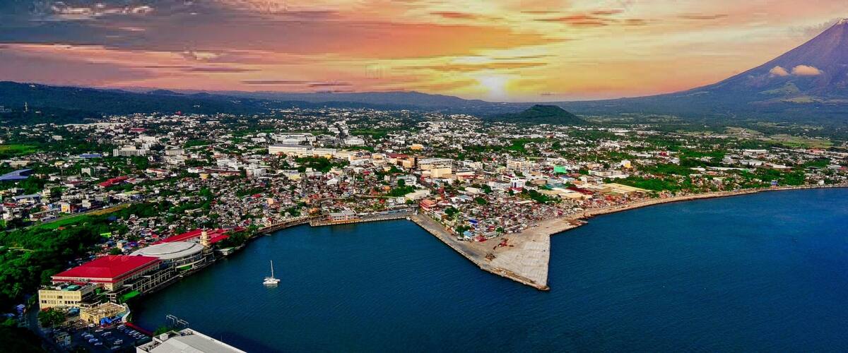 A coastal city with a large volcano in the background.