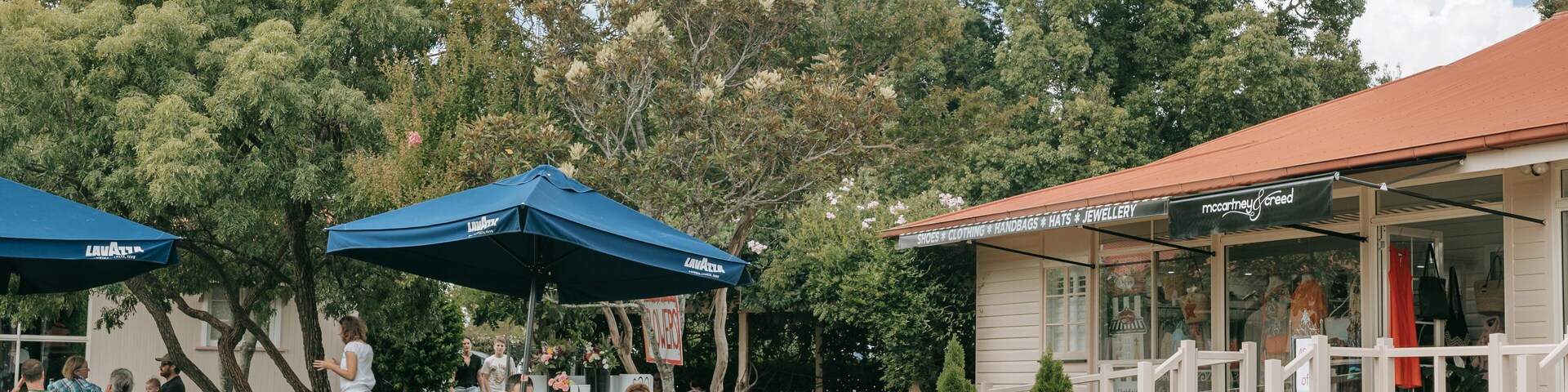 An outdoor cafe with tables and chairs, blue umbrellas, and a building with a sign reading "McCormick & Creed".
