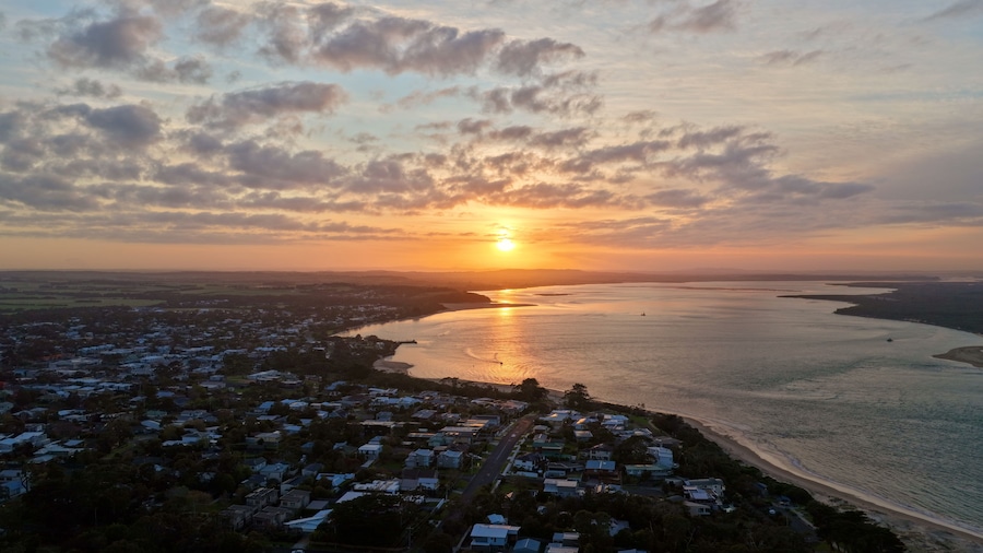 Un pueblo costero al atardecer, con un río y una playa.