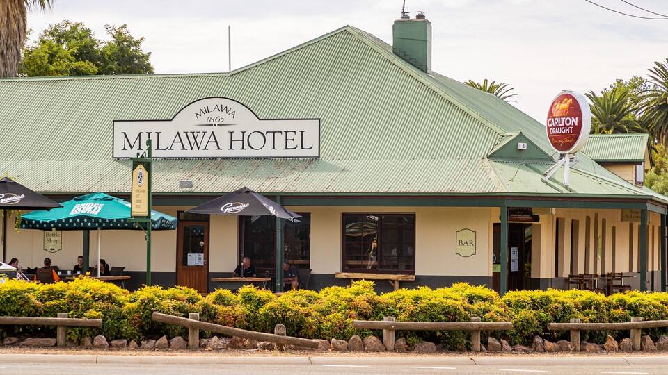 The Milawa Hotel with a green roof, a signboard, and a Carlton Draught sign.