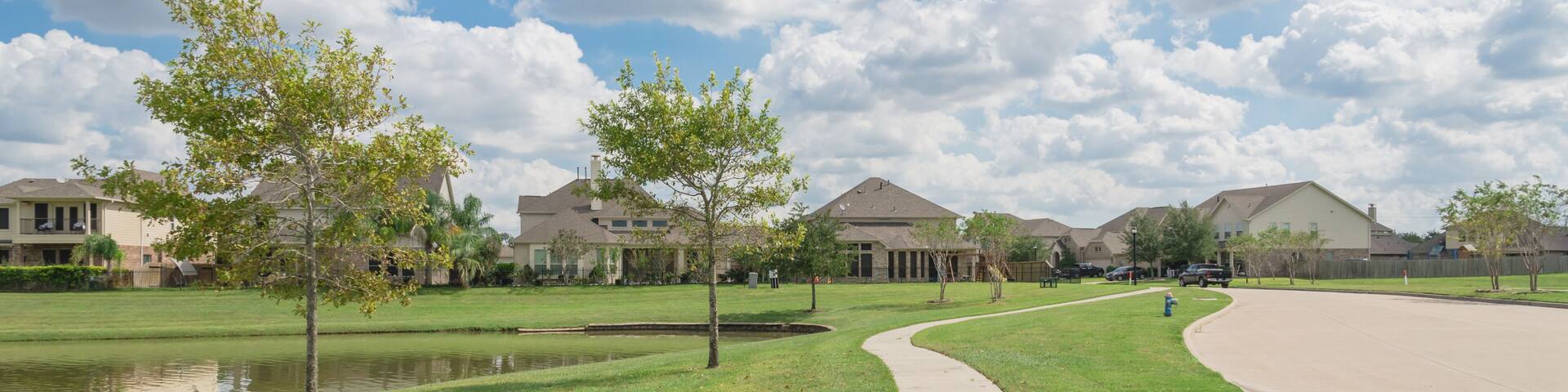 Walking pathway alongside leads to residential houses by the lake in Pearland, Texas, USA. Panorama style.