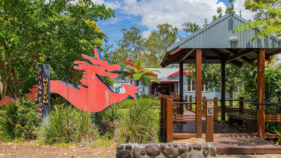 A red sculpture of a fish, a wooden pavilion, and a building with a red roof.