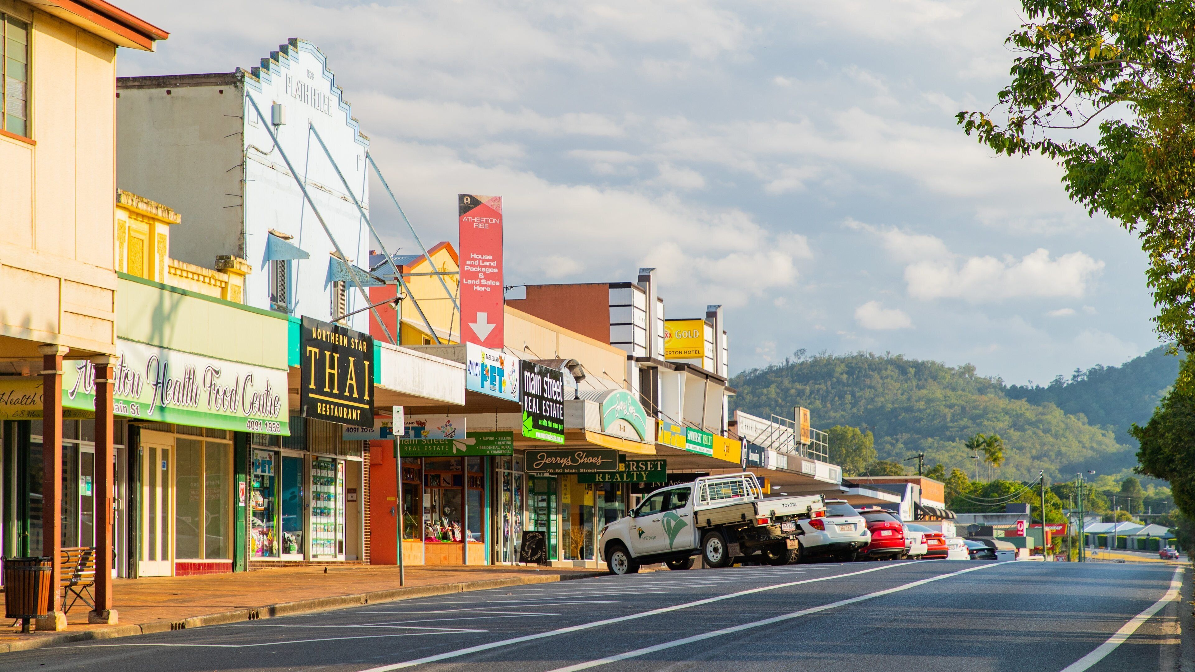 A street lined with various shops and a white truck parked on the side.