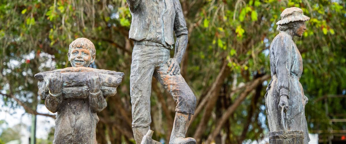 A statue of a man with a hat and a child holding a bucket.