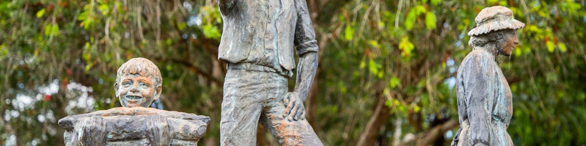 A statue of a man with a hat and a child holding a bucket.
