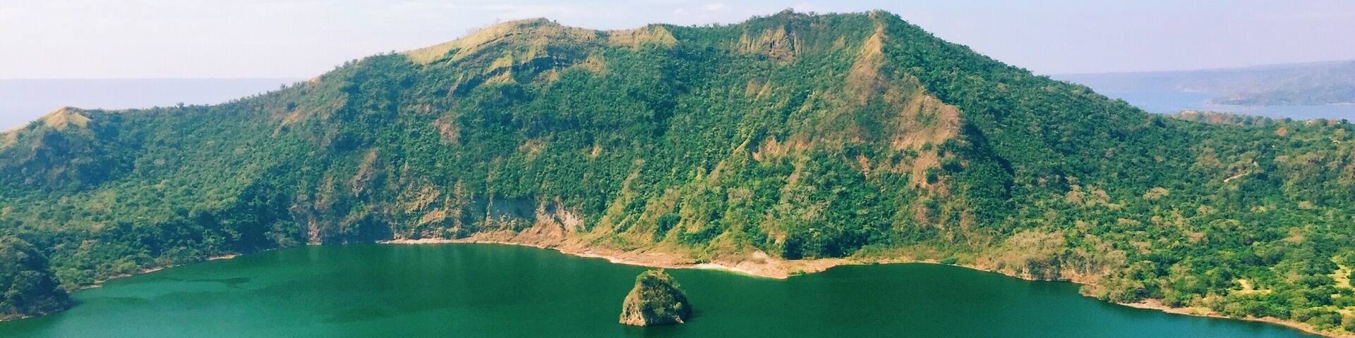 A large green lake surrounded by forested hills.