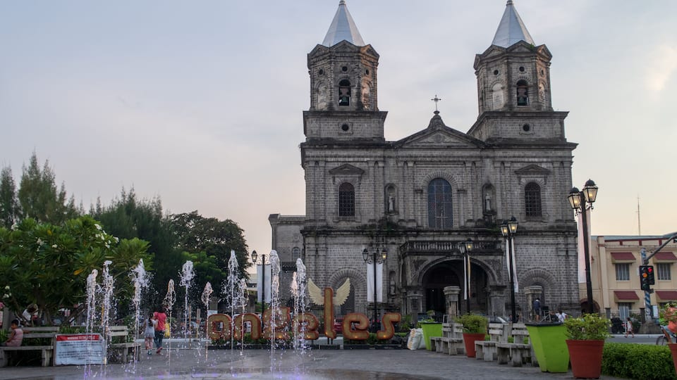 A historic church with twin towers and a fountain in front.