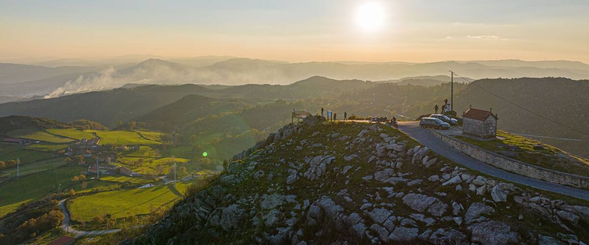 A mountainous landscape with a clear sky, a sunlit peak, and a small stone chapel.