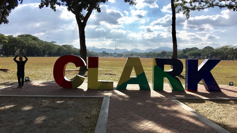 De grandes lettres formant le mot « CLARK » dans un parc, avec des arbres et un champ en arrière-plan.