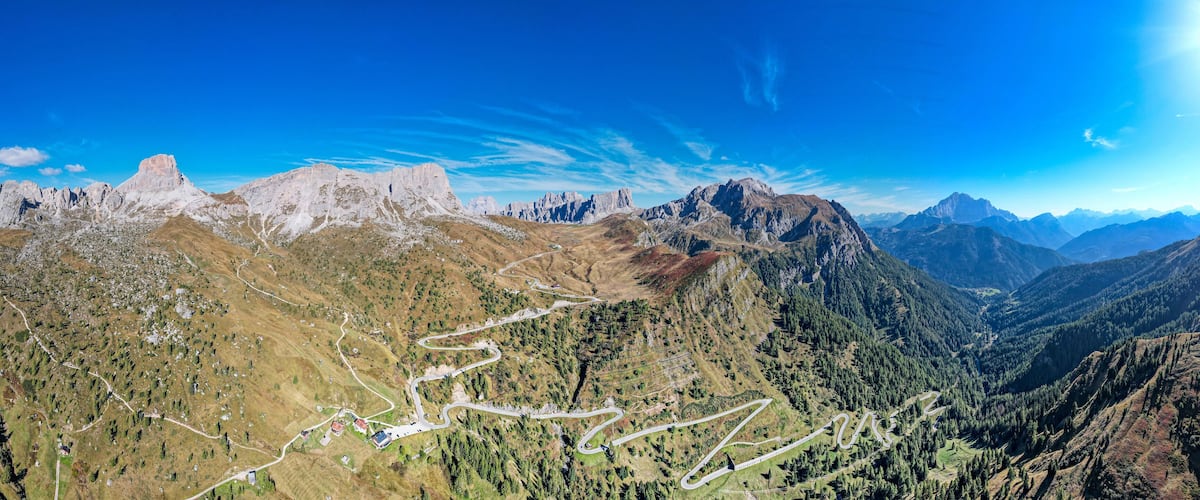A mountainous landscape with winding roads and a clear blue sky.