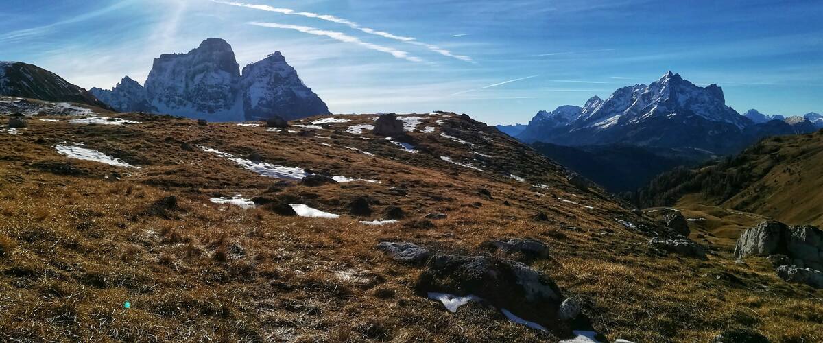 A mountainous landscape with snow patches and a clear sky.