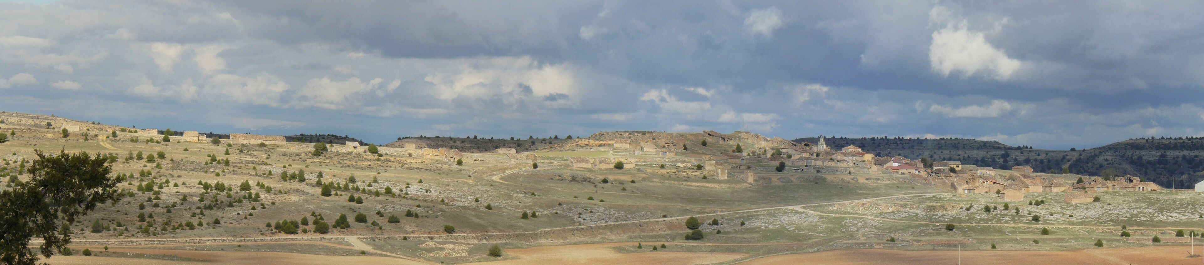 A hilly landscape with scattered buildings and trees.