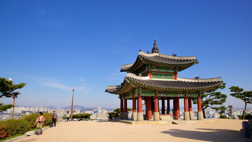 A traditional Korean pavilion with ornate architecture, set against a cityscape backdrop.
