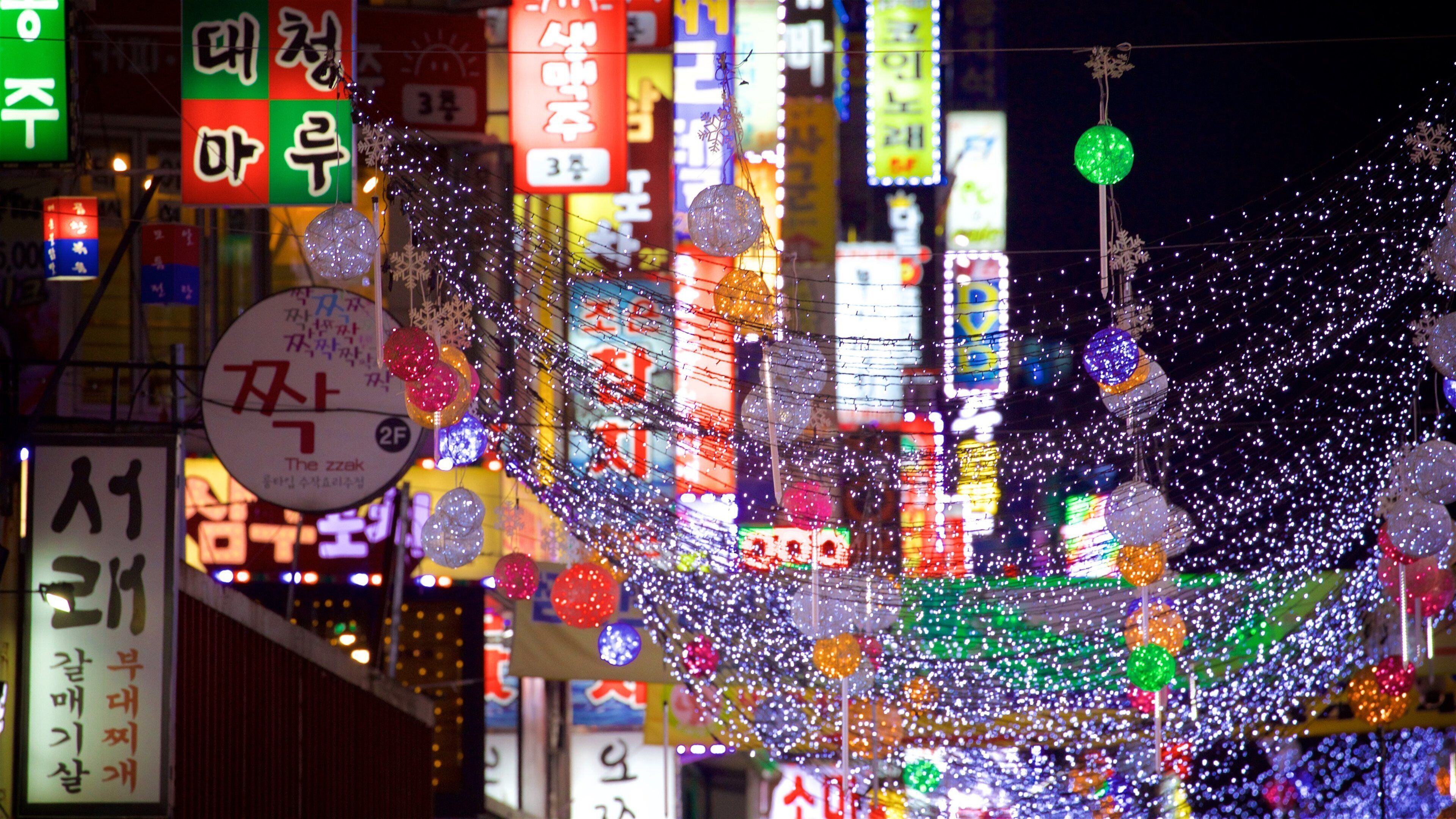 A vibrant night scene with illuminated signs and decorations, including a prominent '3F' sign and various colorful lights.