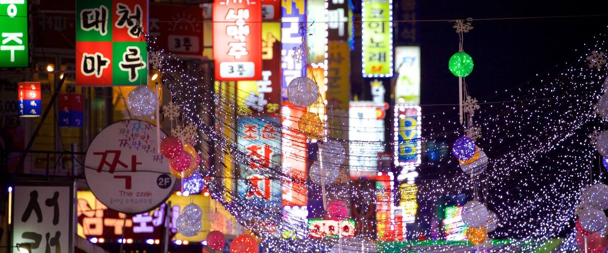 A vibrant night scene with illuminated signs and decorations, including a prominent '3F' sign and various colorful lights.