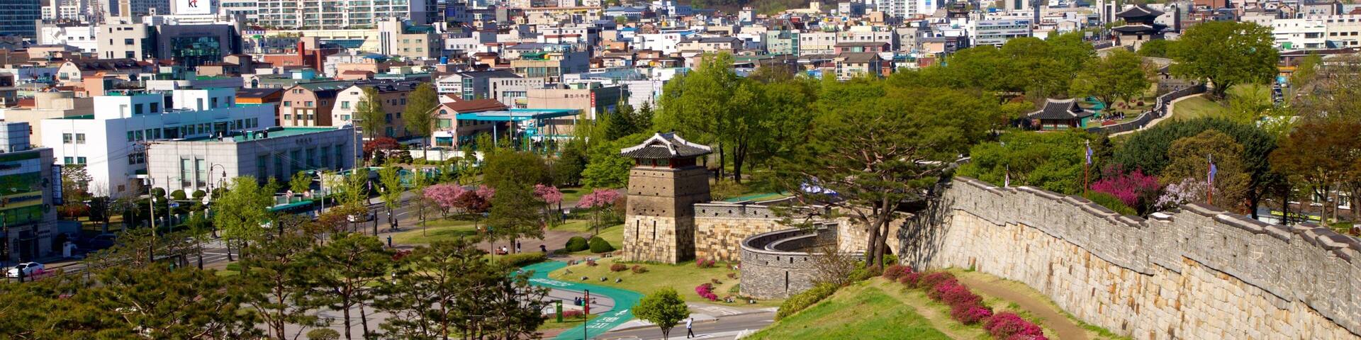A cityscape with modern buildings, a traditional stone tower, and a river.
