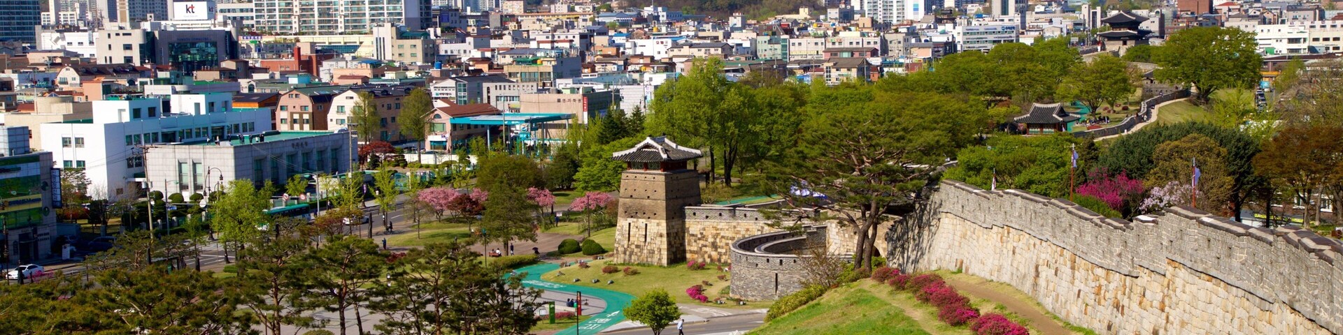 Un paisaje urbano con edificios modernos, una torre de piedra tradicional y un río.