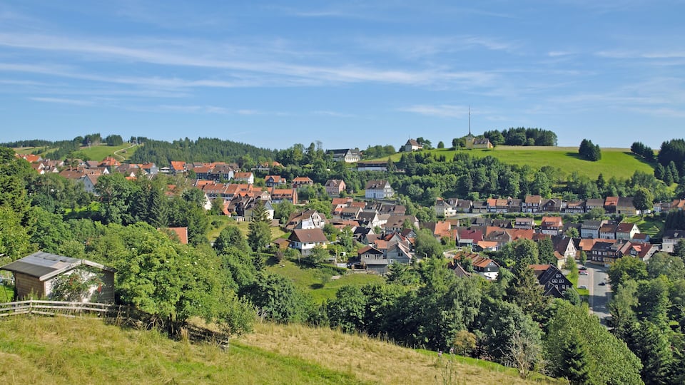 A picturesque village with red-roofed houses nestled in green hills.