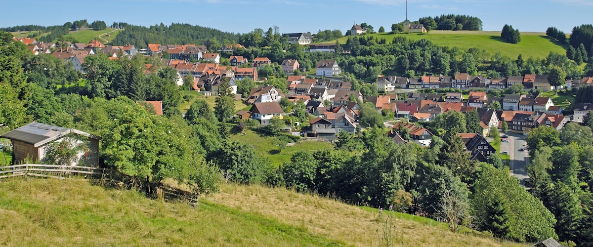 A picturesque village with red-roofed houses nestled in green hills.
