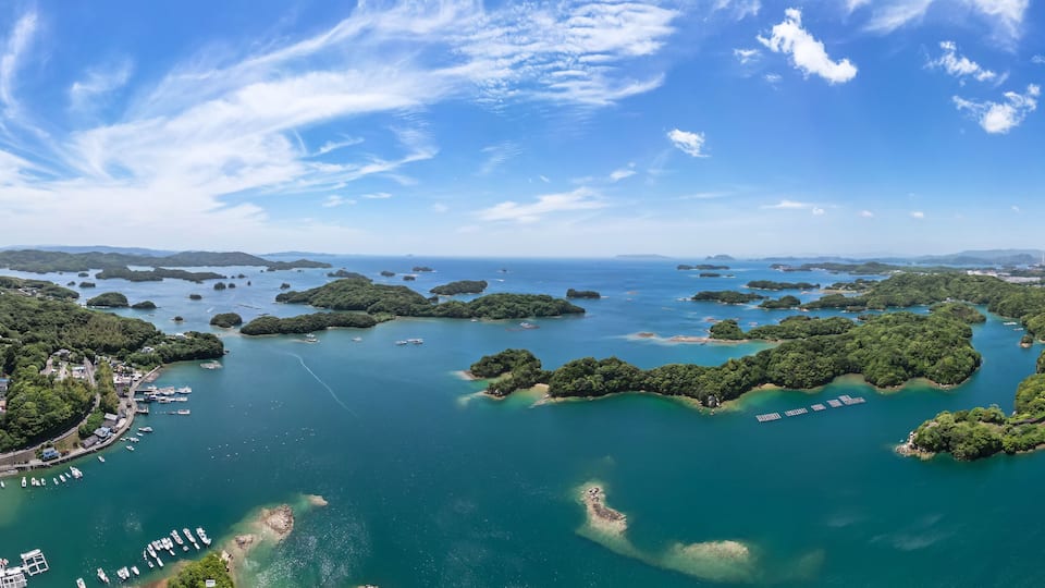 A coastal town with a marina, surrounded by lush green islands and clear blue waters.